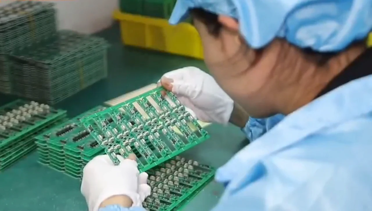 Gloved operator handling a panel of circuit boards